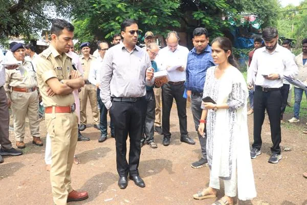 खुले स्थान पर पुलिस अधिकारी और प्रशासनिक अधिकारियों से बातचीत करती महिला अधिकारी, पीछे अन्य कर्मचारी खड़े हैं